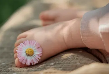 Babyfuß mit Blume zwischen Zehen
