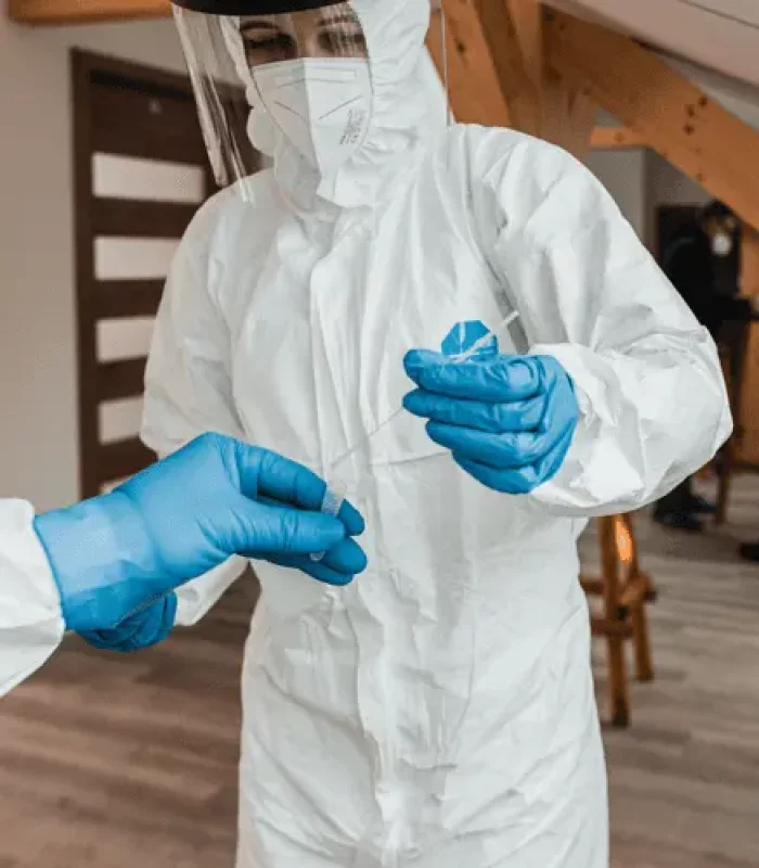 Person im weißen Schutzanzug mit Teströhrchen