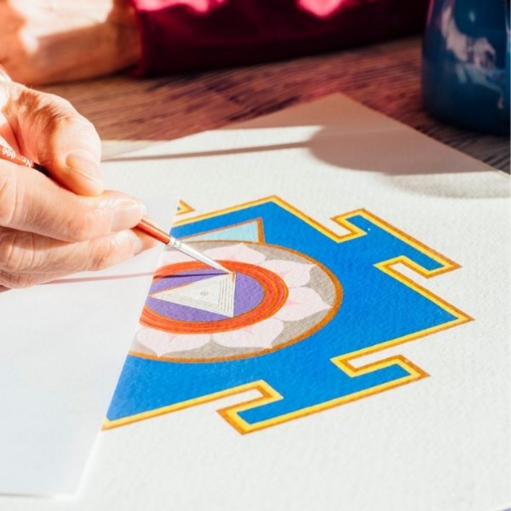 Blaues Yantra auf weißem Grund, das gerade ausgemalt wird